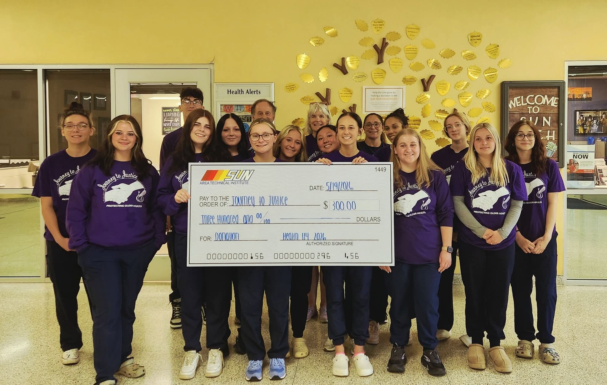Journey to Justice representatives accepting a donation check from Sun Tech health career students and their teacher